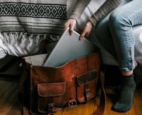 Woman in Gray Long Sleeve Shirt and Blue Denim Jeans Sitting on Gray Couch