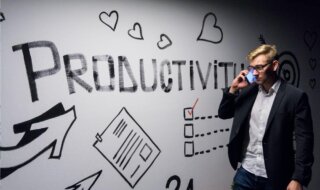 man holding smartphone looking at productivity wall decor