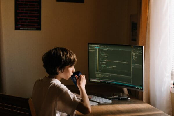 A child sitting at a desk playing a video game Description automatically generated with low confidence