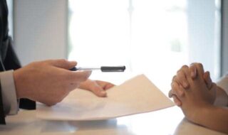 A person holding a pen over a paper Description automatically generated