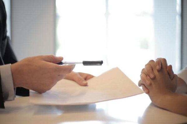 A person holding a pen over a paper Description automatically generated